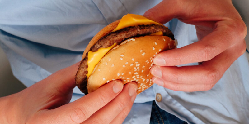 individual holding a cheeseburger
