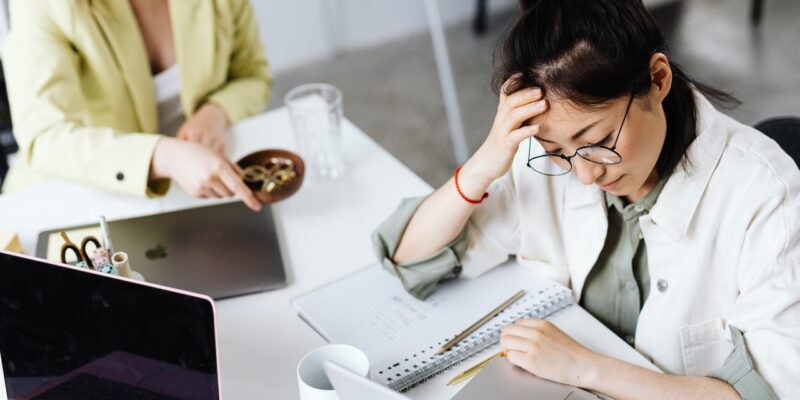 Frustrated woman sitting at desk trying to cope with stress at work.